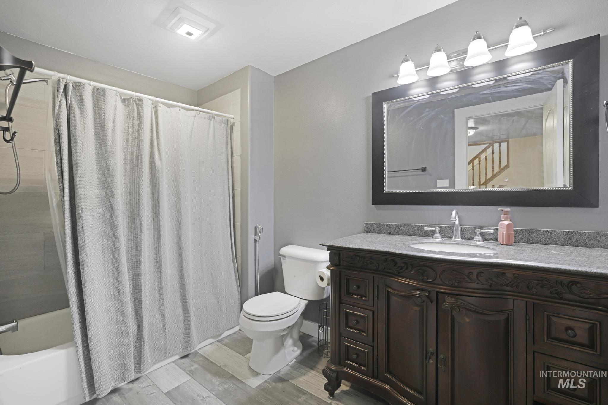Bathroom featuring shower / bath combination with curtain, light wood-type flooring, and vanity