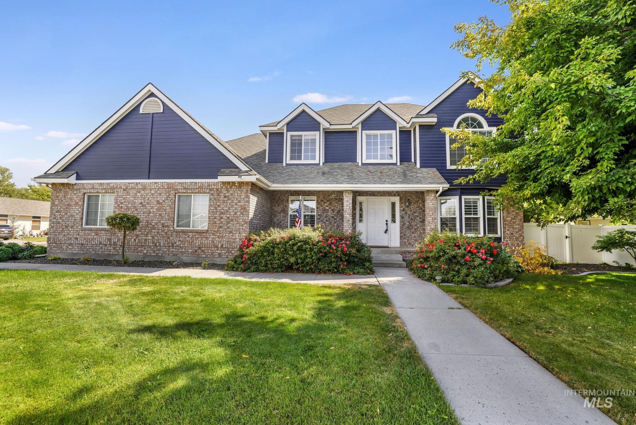 Traditional-style home featuring covered porch, brick siding, and a shingled roof