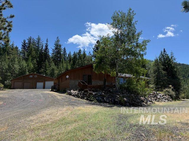 View of property exterior featuring a garage, an outbuilding, and a wooded view