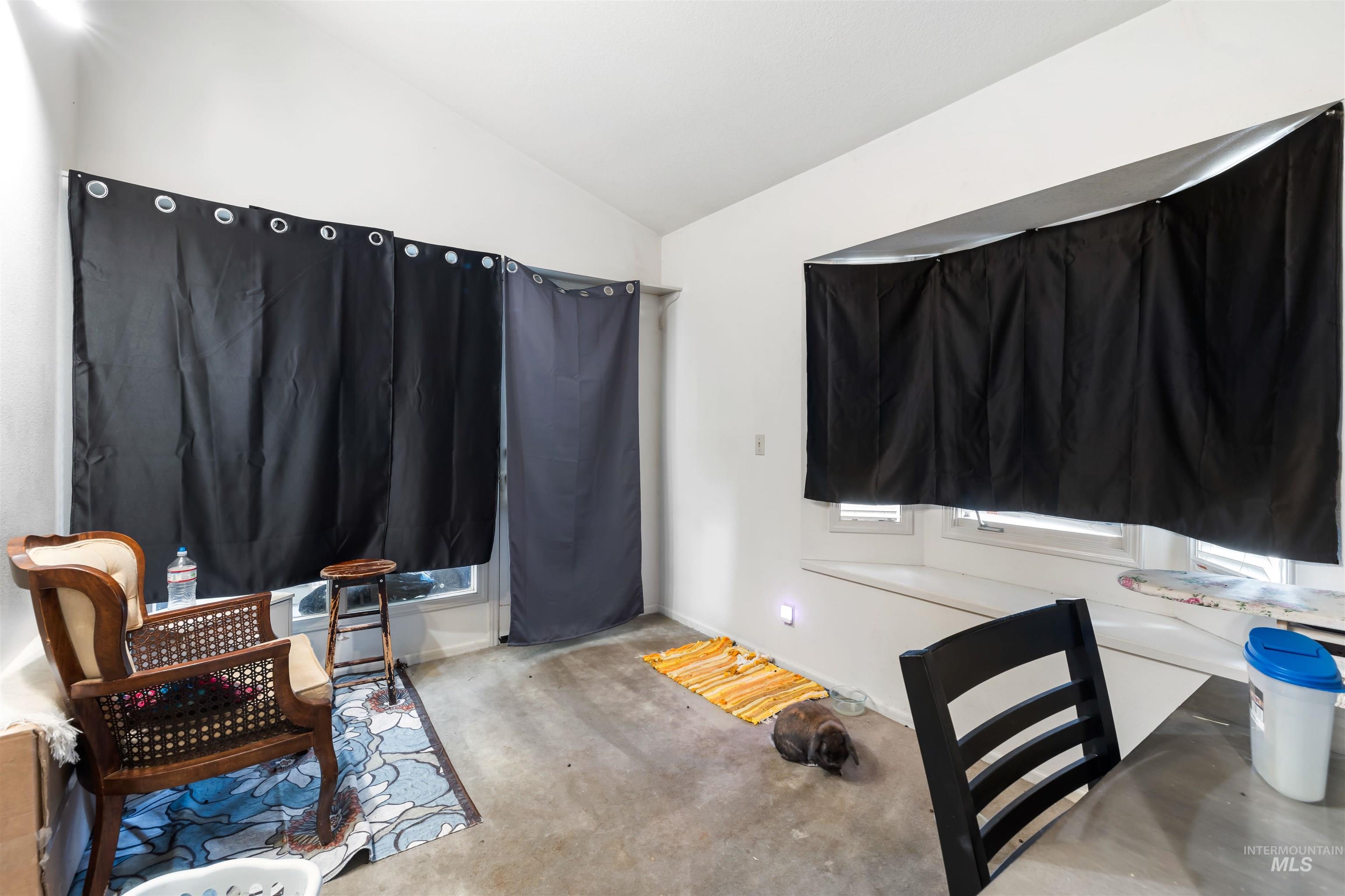 Carpeted office space featuring vaulted ceiling and baseboards