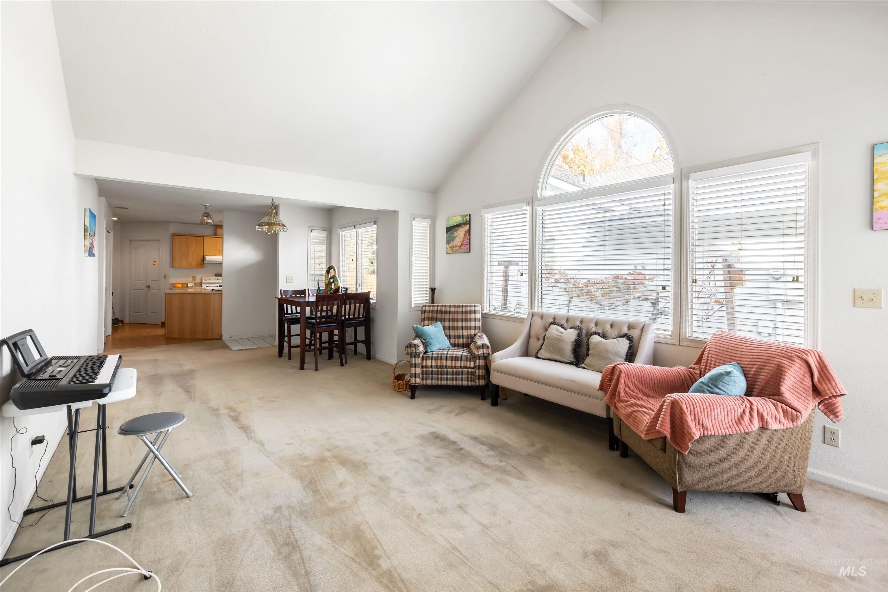 Living room featuring light carpet, high vaulted ceiling, and beam ceiling