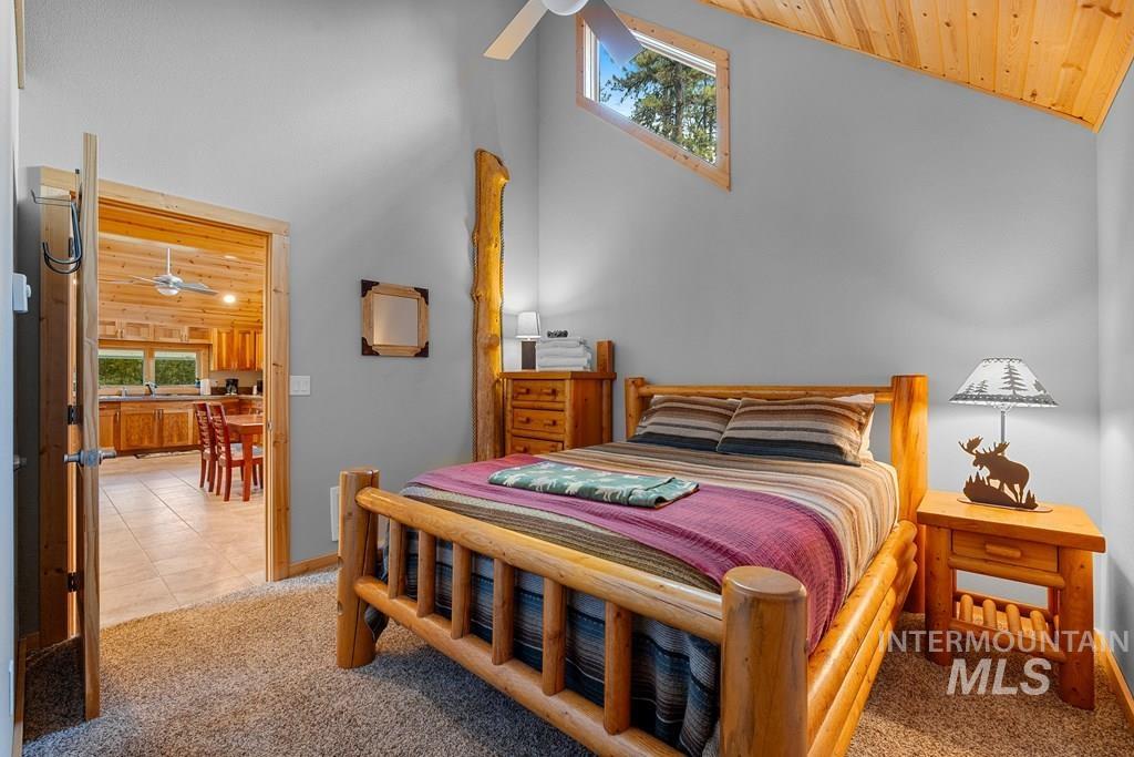 Bedroom featuring vaulted wood-paneled ceilings, a ceiling fan, and a wood-frame bed
