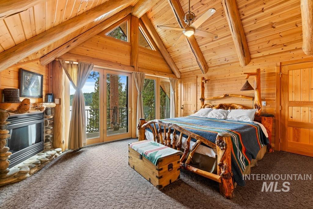 Wood-paneled room featuring a stone-faced fireplace, vaulted wood-beam ceiling, and an integrated ceiling fan