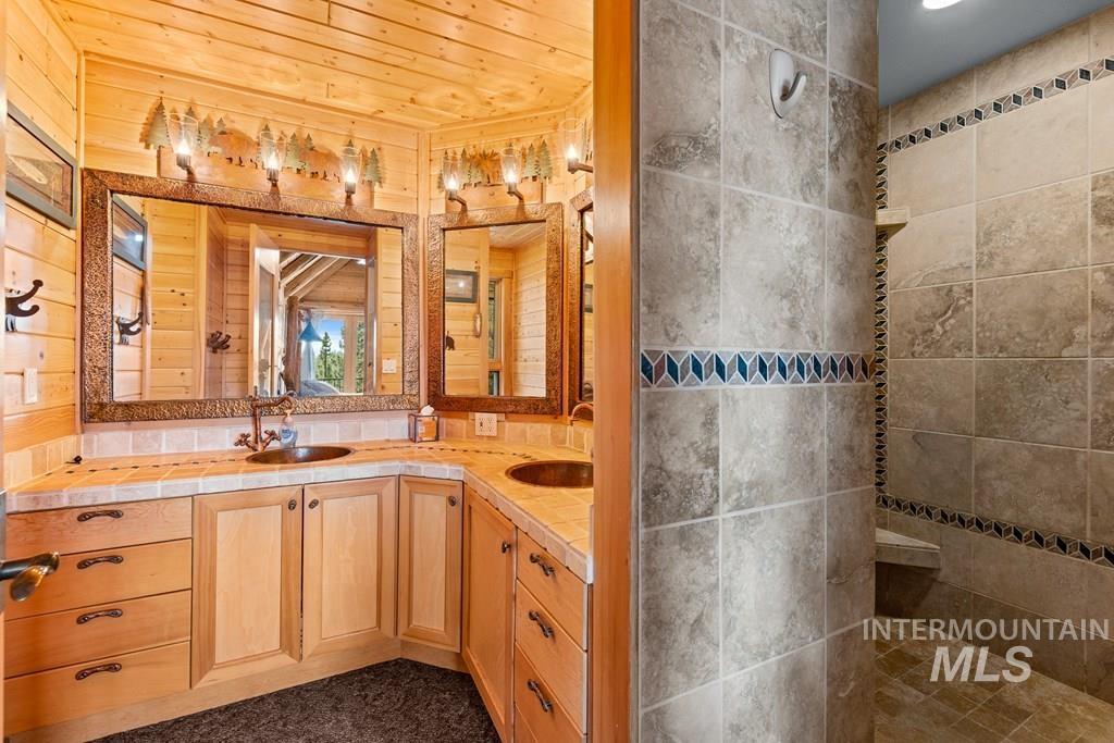 Dual vanity with wood cabinetry and copper sinks, set against wood-paneled walls
