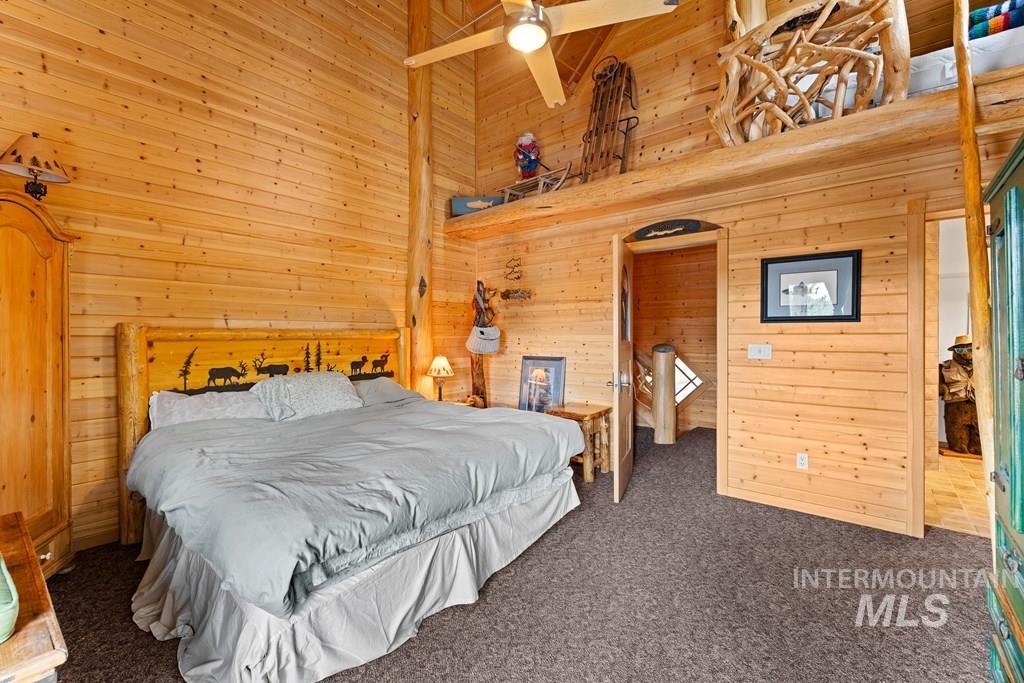 Interior space featuring extensive wood paneling, a vaulted ceiling, and a ceiling fan