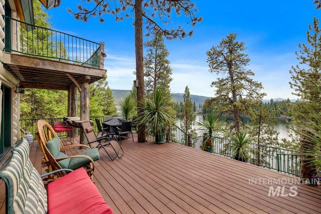 Spacious outdoor deck with wood-finish flooring, metal railings, and a lower-level covered patio featuring natural wood support columns