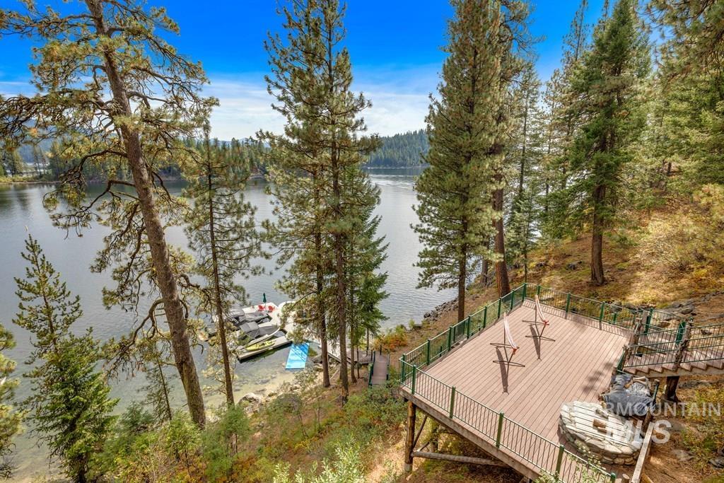 Elevated waterside deck with composite decking and metal railings, featuring a built-in stone fire pit