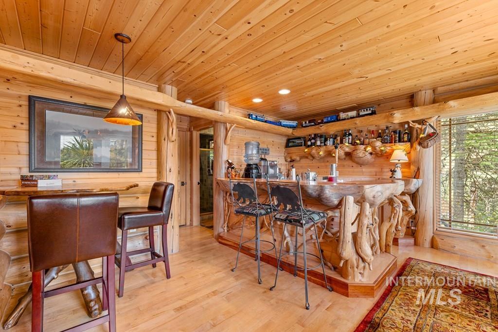 Custom-crafted wood bar with built-in shelving, wood-paneled walls, wood-finish flooring, and a large window