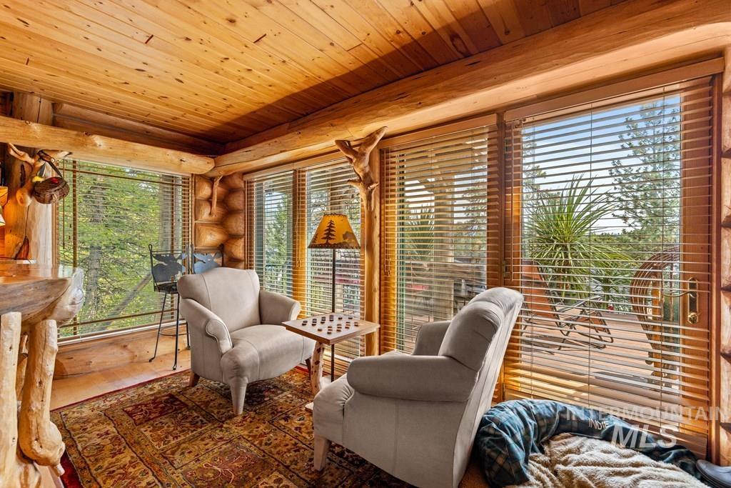 Room featuring expansive windows, wood-paneled ceiling, and log walls