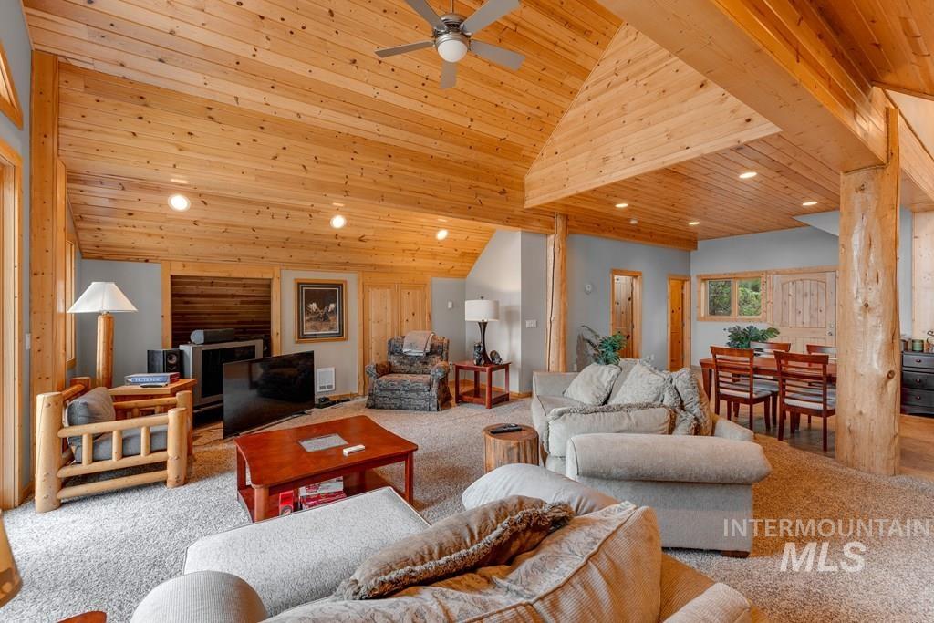Expansive living area with vaulted wood plank ceilings, recessed lighting, and exposed log posts