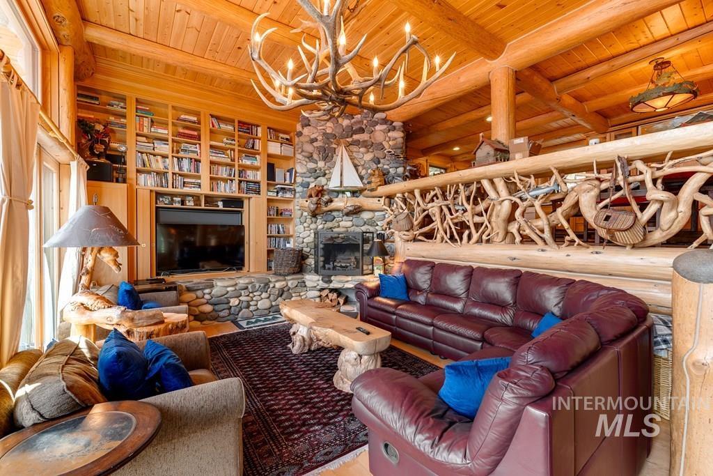 Expansive living area featuring exposed log beams, plank wood ceilings, and a stone-clad fireplace