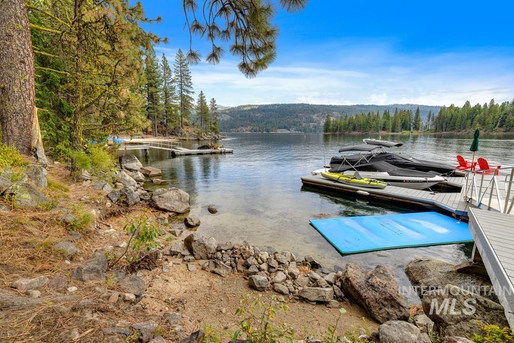Waterfront property featuring a private dock system, direct lake access, a natural shoreline with large boulders, and mature evergreen trees
