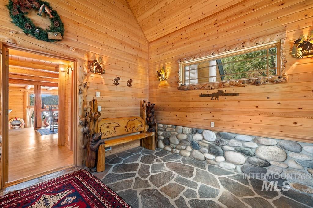Entryway featuring natural wood paneling, a stone accent wall, and flagstone flooring