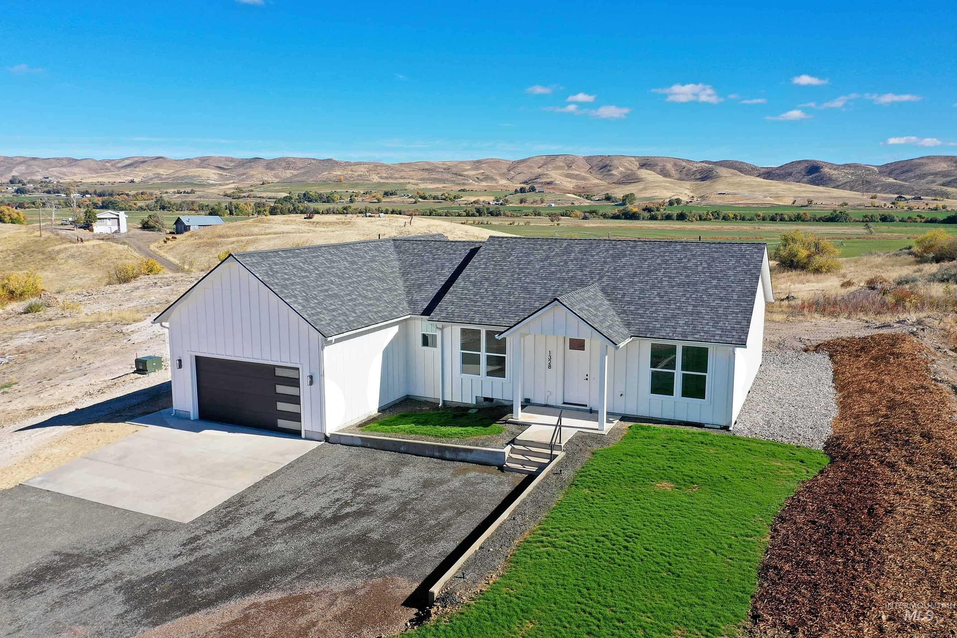 Modern farmhouse style home featuring board and batten siding, driveway, a shingled roof, a mountain view, and a view of countryside