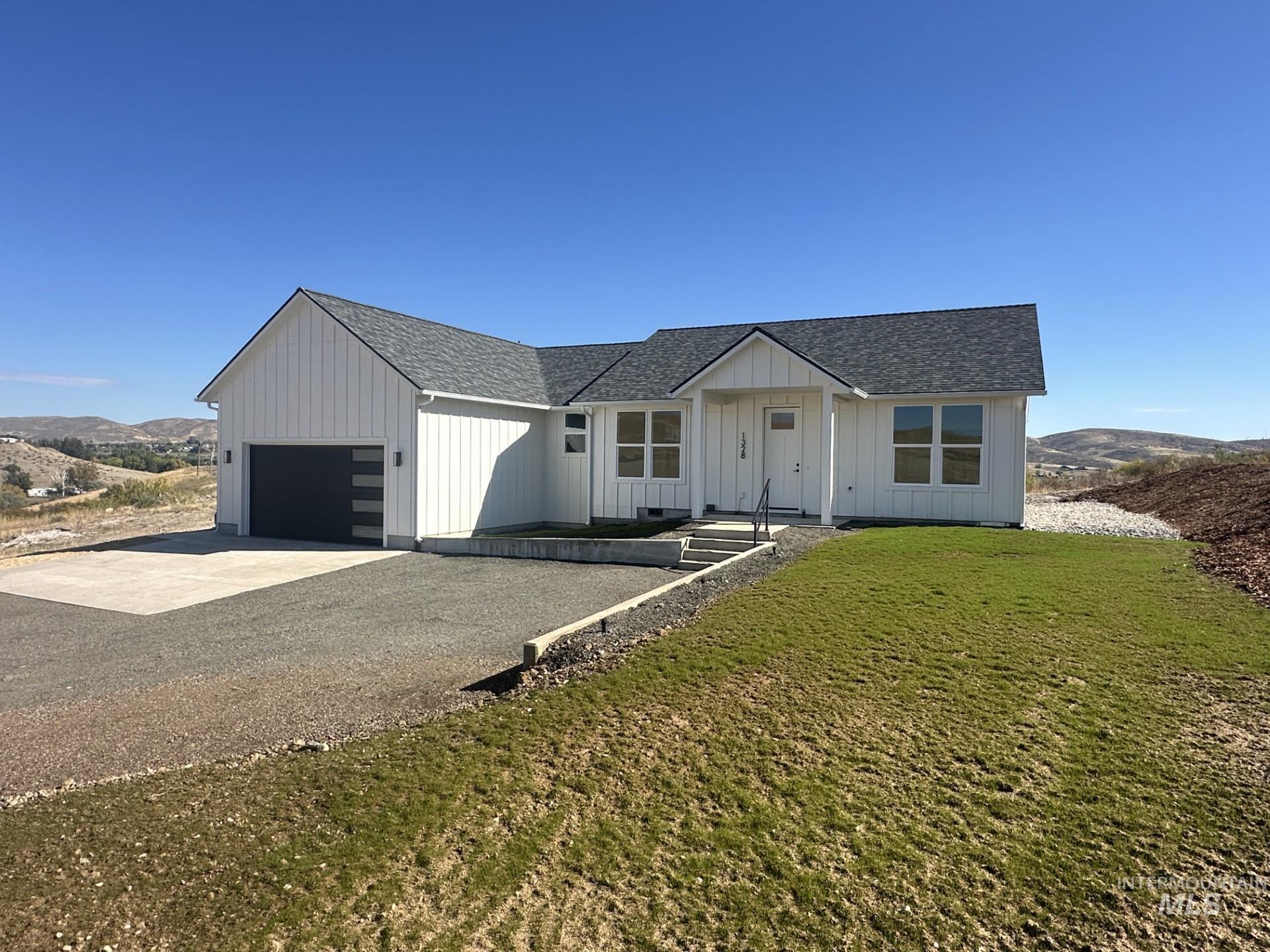 Modern farmhouse style home featuring board and batten siding, roof with shingles, driveway, and a front yard