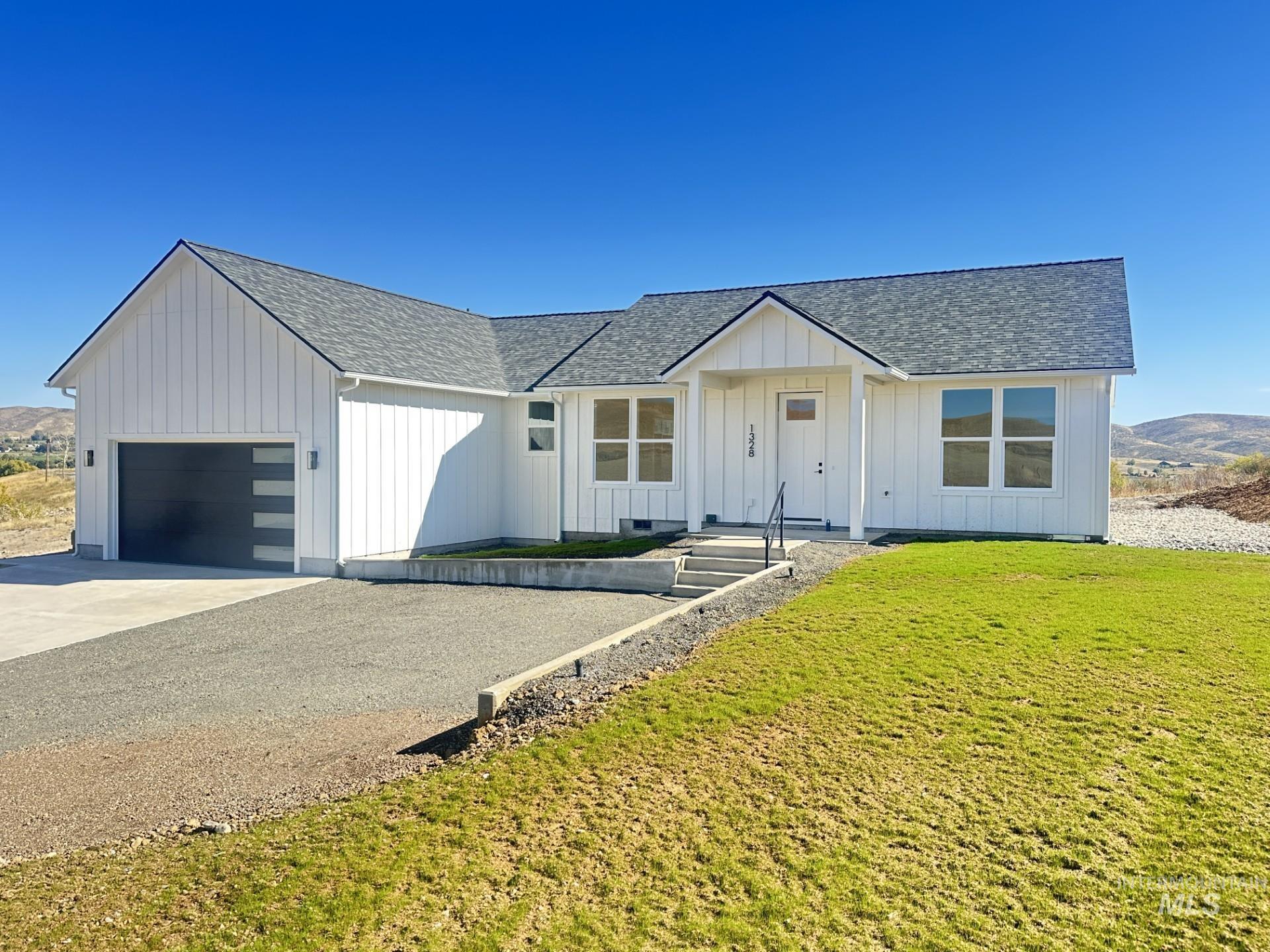 Modern farmhouse style home featuring a shingled roof, board and batten siding, concrete driveway, a front lawn, and a garage