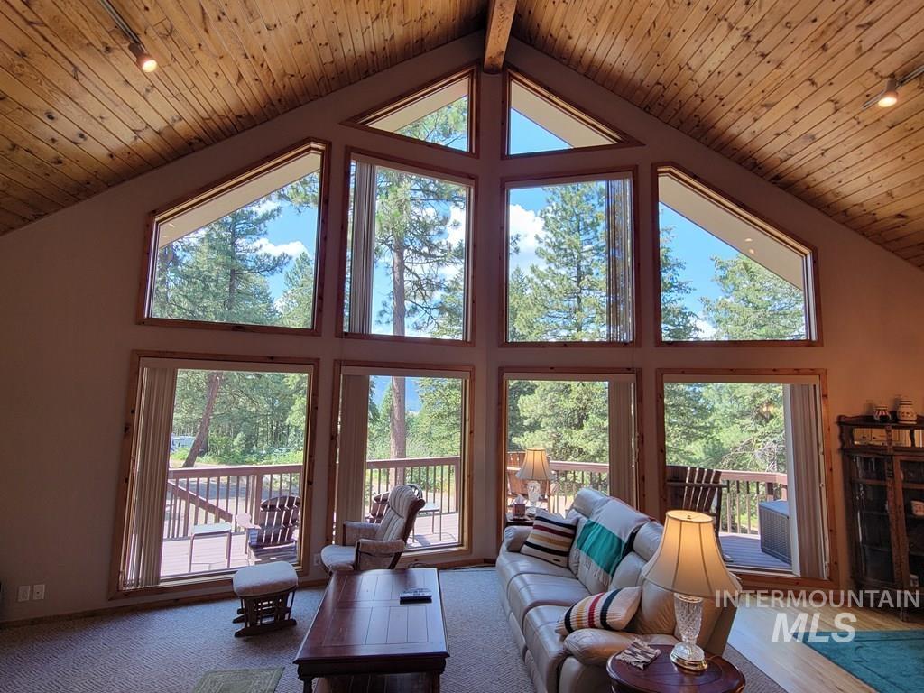 Living room with healthy amount of natural light, high vaulted ceiling, and a wood ceiling with exposed beams