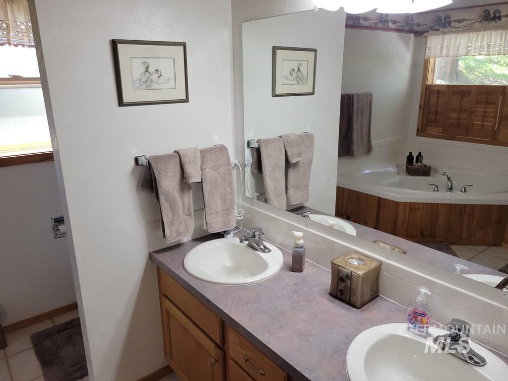Bathroom with a garden tub, double vanity, and light tile patterned flooring