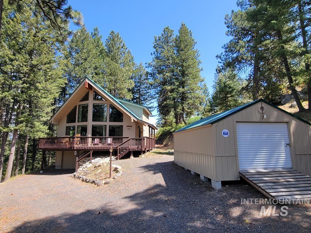 View of front facade with a wooden deck, an outdoor structure, and gravel driveway