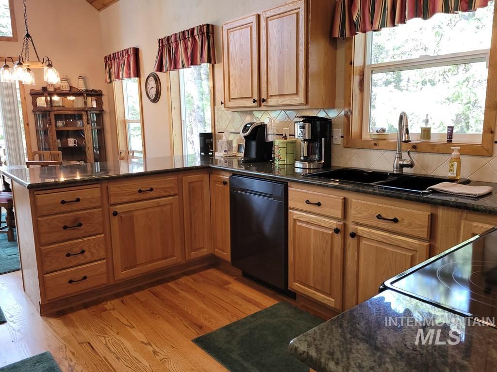 Kitchen featuring decorative backsplash, dark stone counters, a peninsula, and brown cabinetry