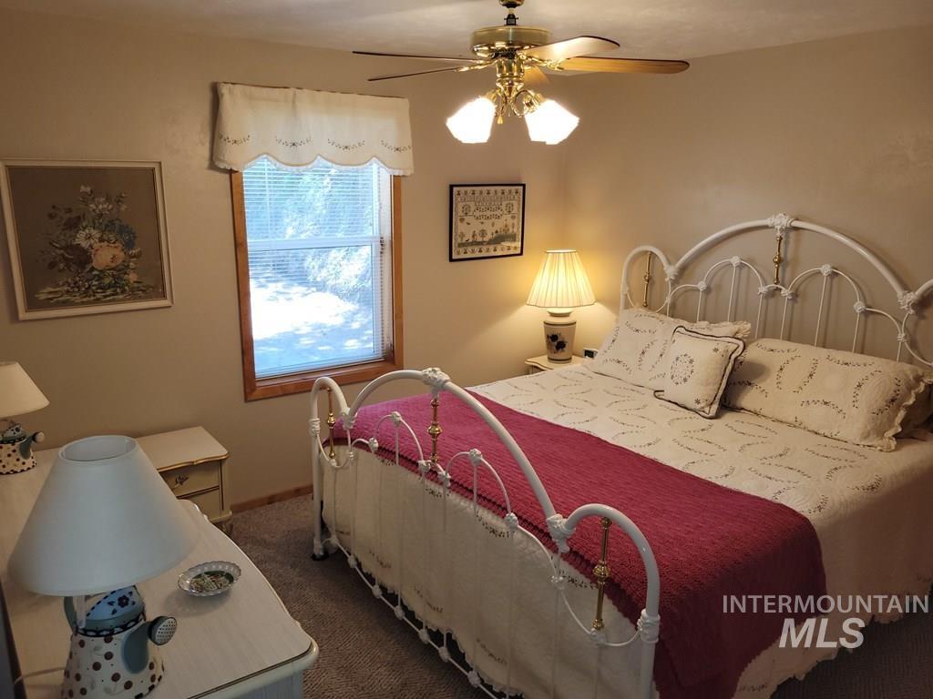 Bedroom with a ceiling fan and dark carpet