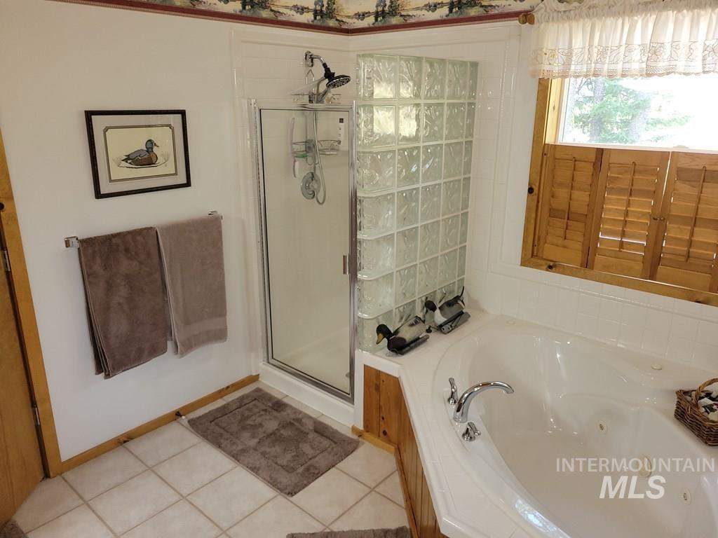 Bathroom featuring a whirlpool tub, a shower stall, and light tile patterned floors