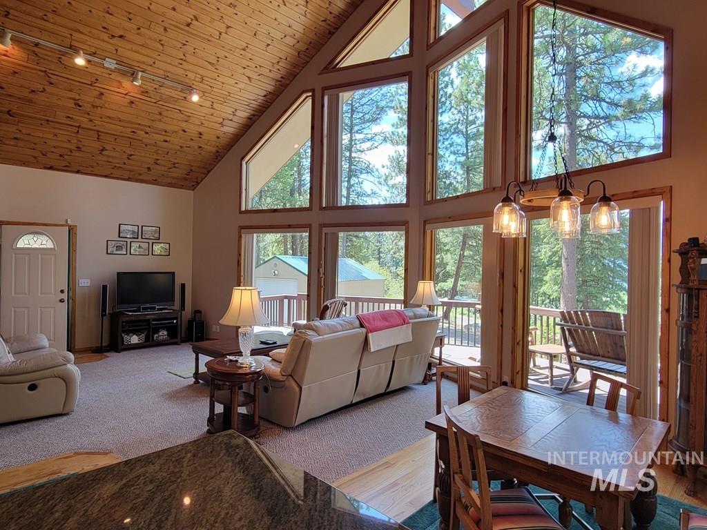 Carpeted living area featuring high vaulted ceiling and wood ceiling