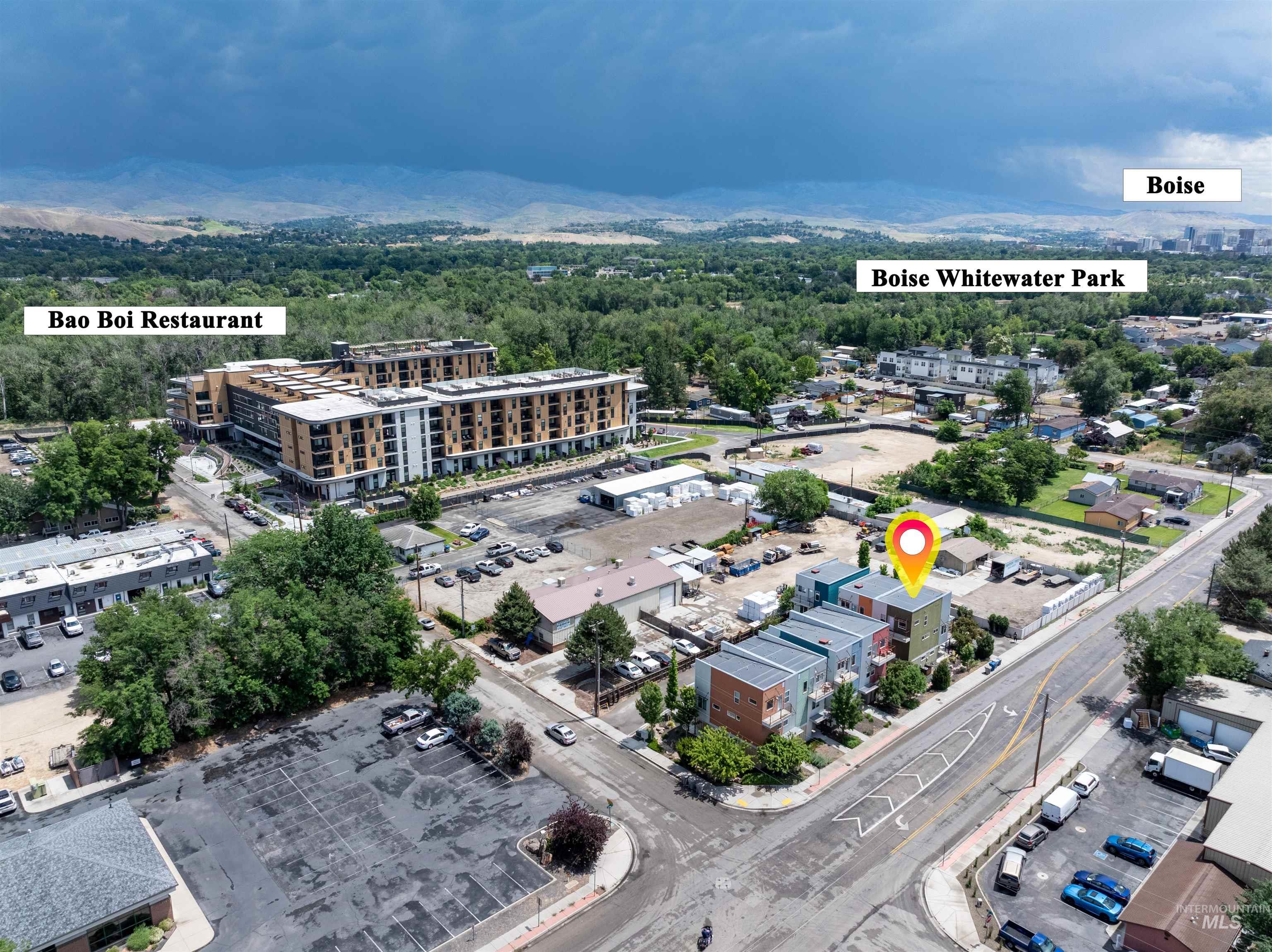 Aerial perspective highlighting modern townhomes with colorful facades, paved street access, and a dense urban setting