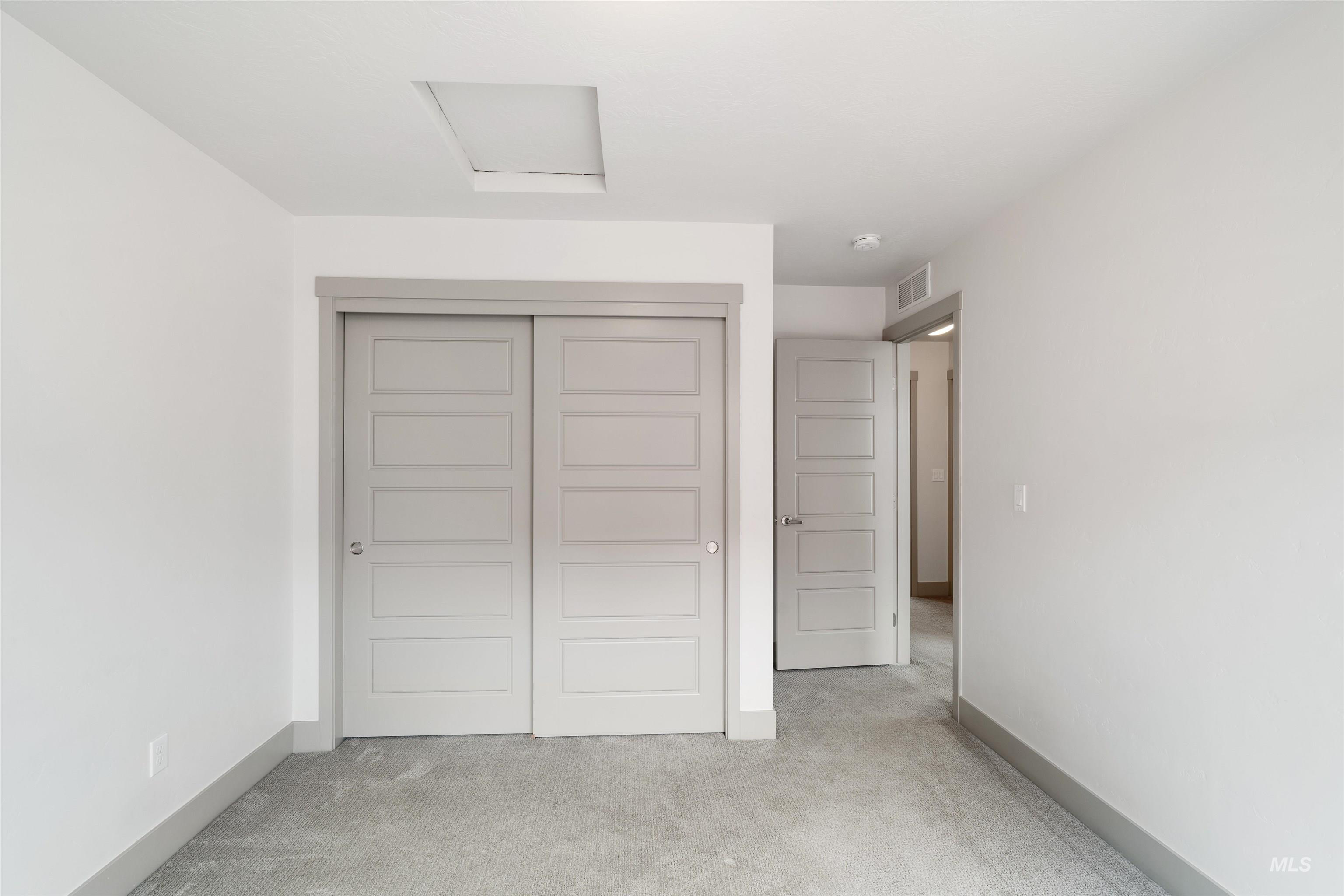Interior room featuring light gray carpet flooring, white walls, and gray baseboards