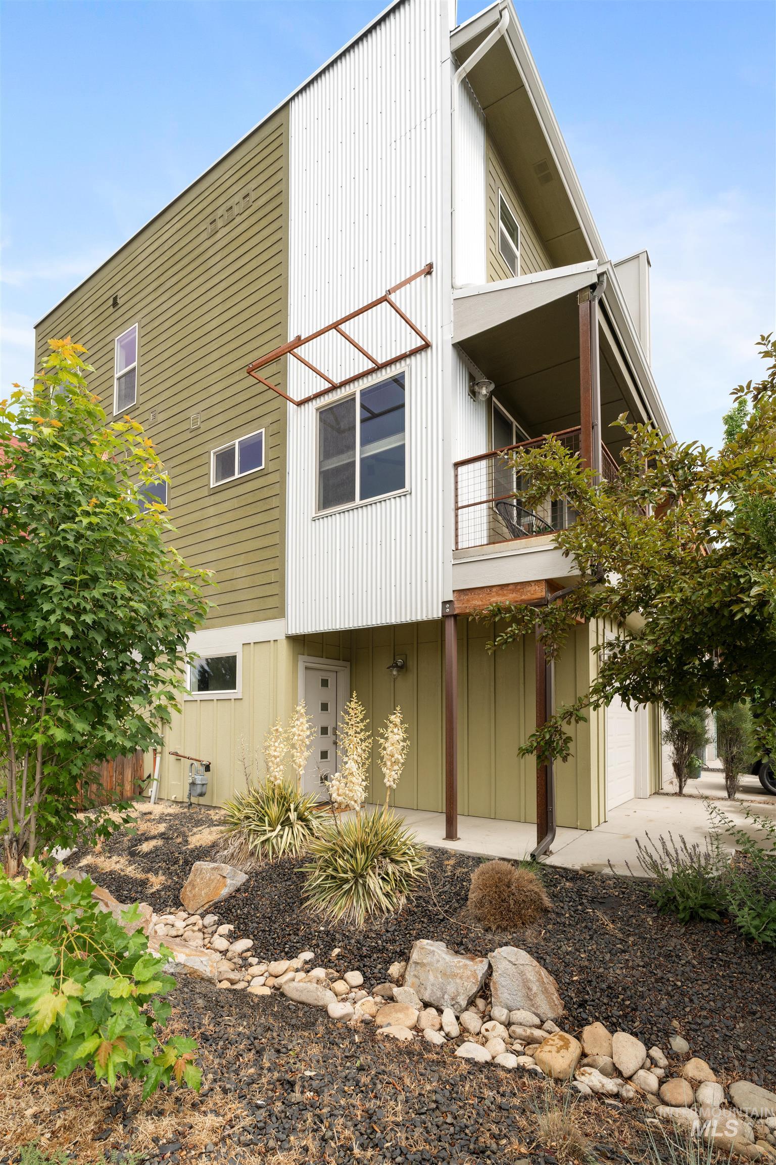 Contemporary exterior featuring olive-toned siding and vertical white corrugated metal accents