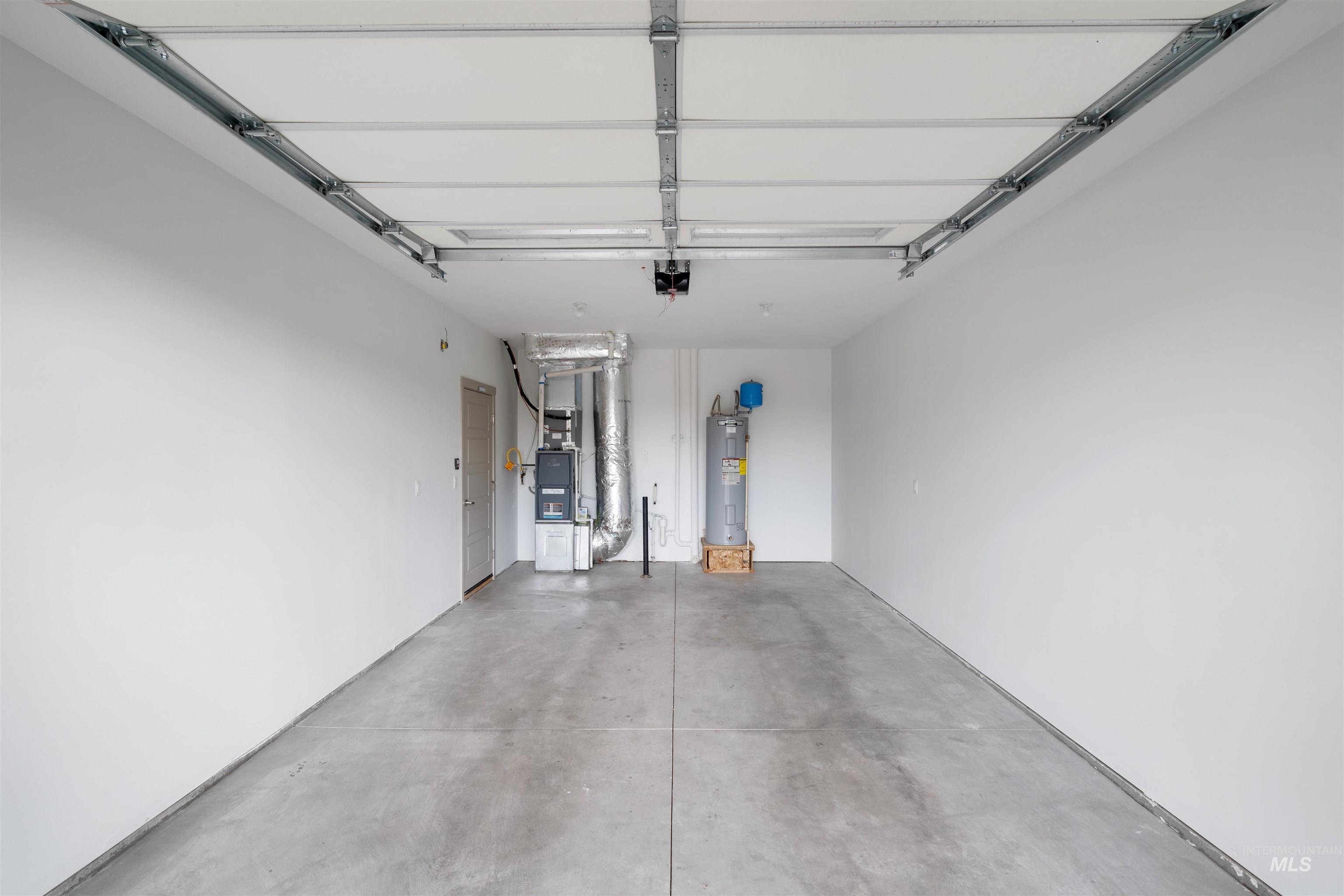 Garage with a concrete floor, white painted walls, and an overhead garage door track system