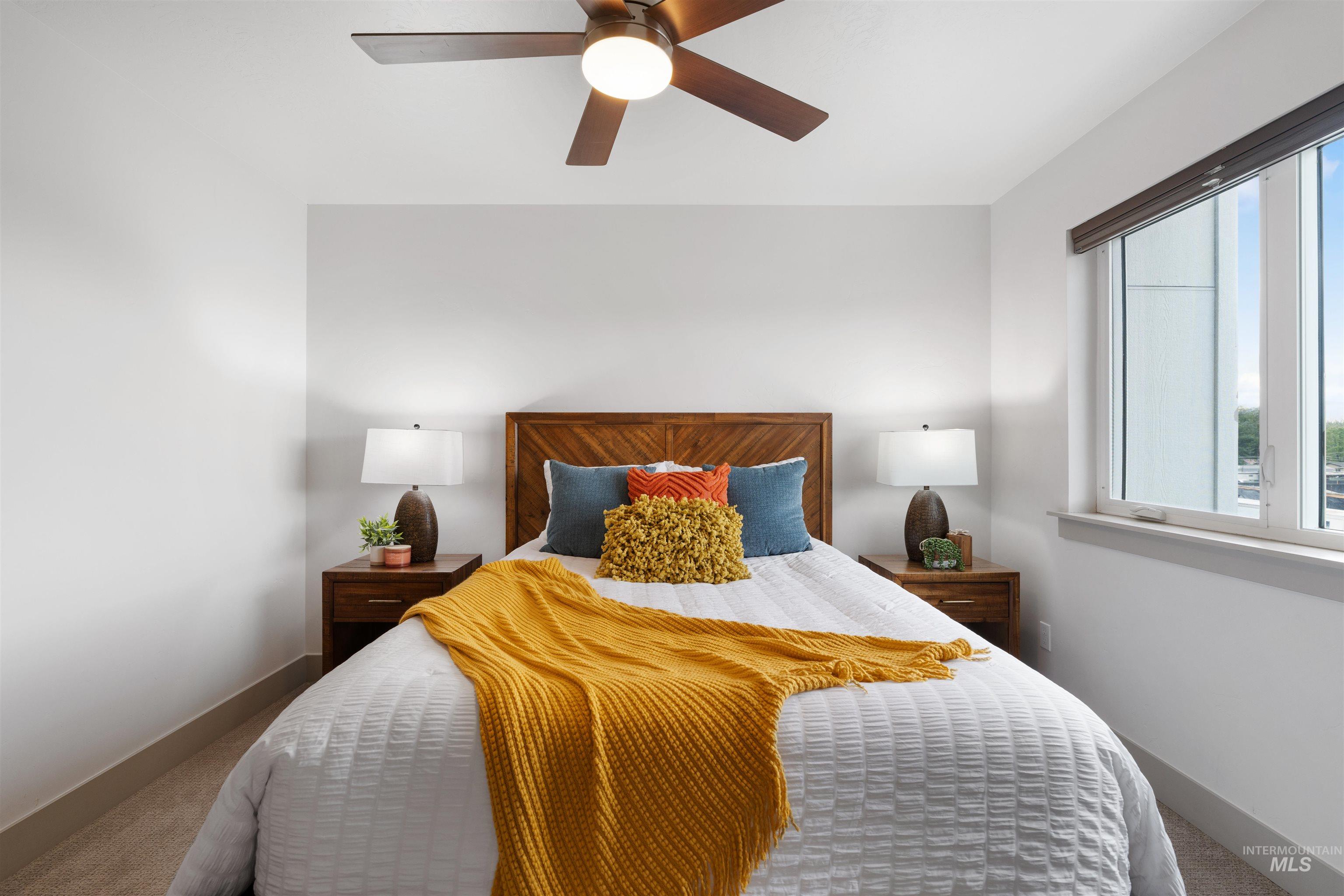 Bedroom featuring a wood-panel headboard, recessed window, ceiling fan with integrated lighting, and carpeted flooring