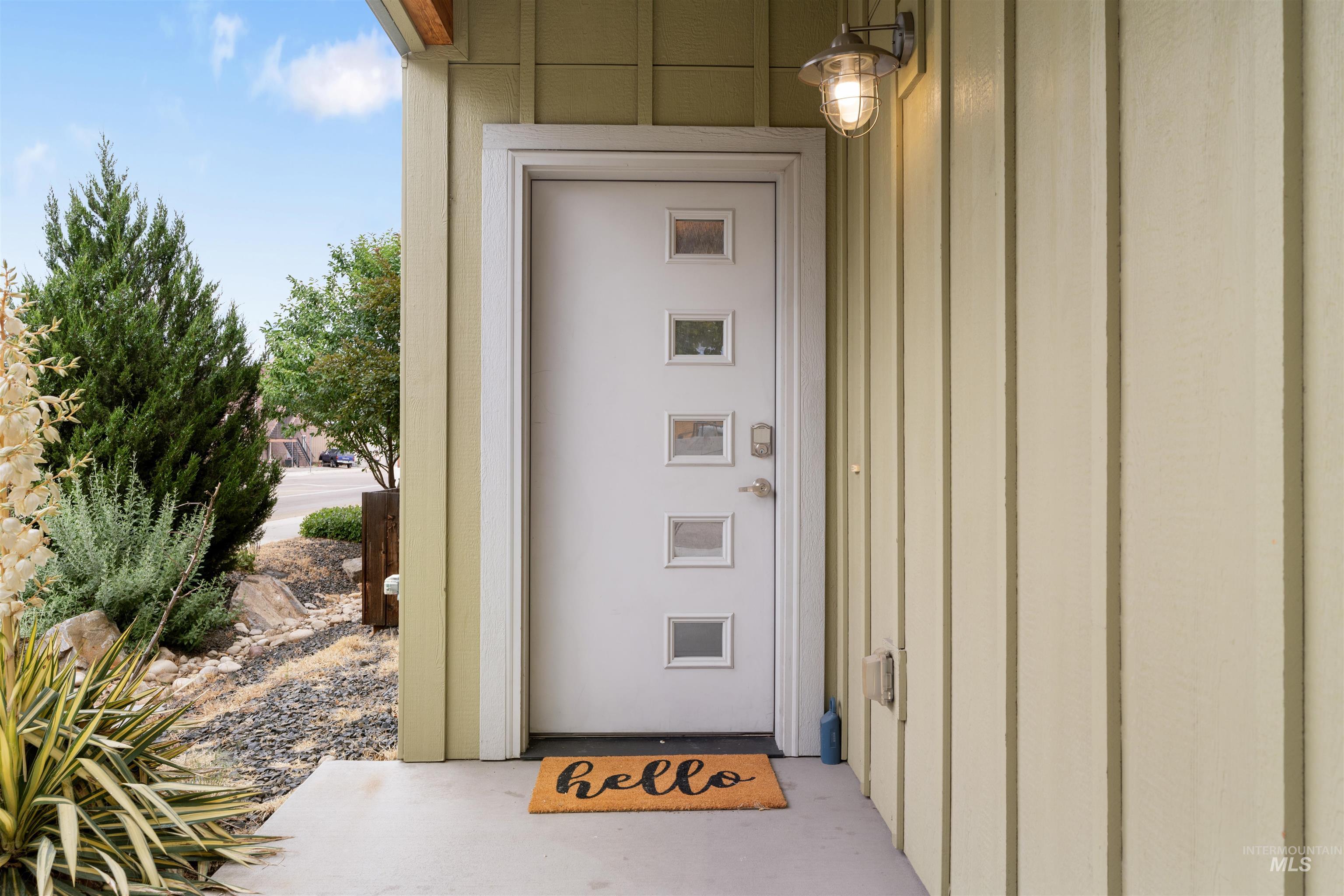 Modern entry door with five square lites and brushed nickel hardware, complemented by board and batten siding