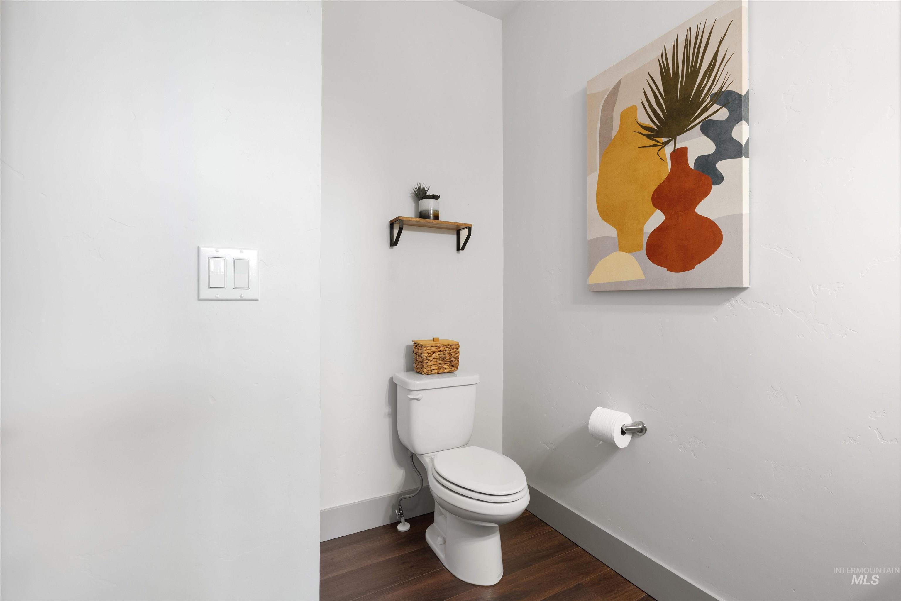 White ceramic toilet with dark wood-finish flooring