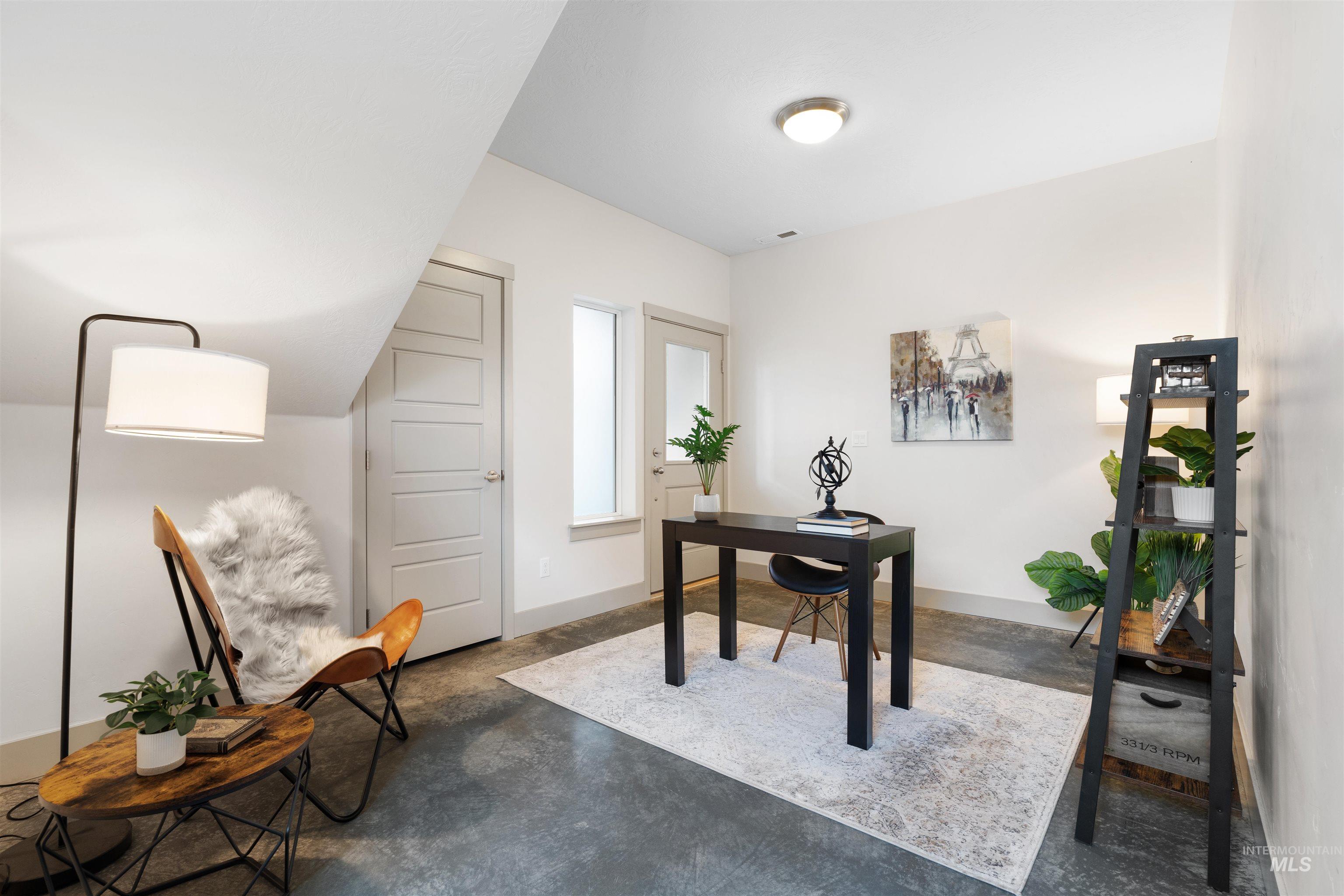 Attic space featuring concrete flooring, an accent wall, two panel doors, and a window