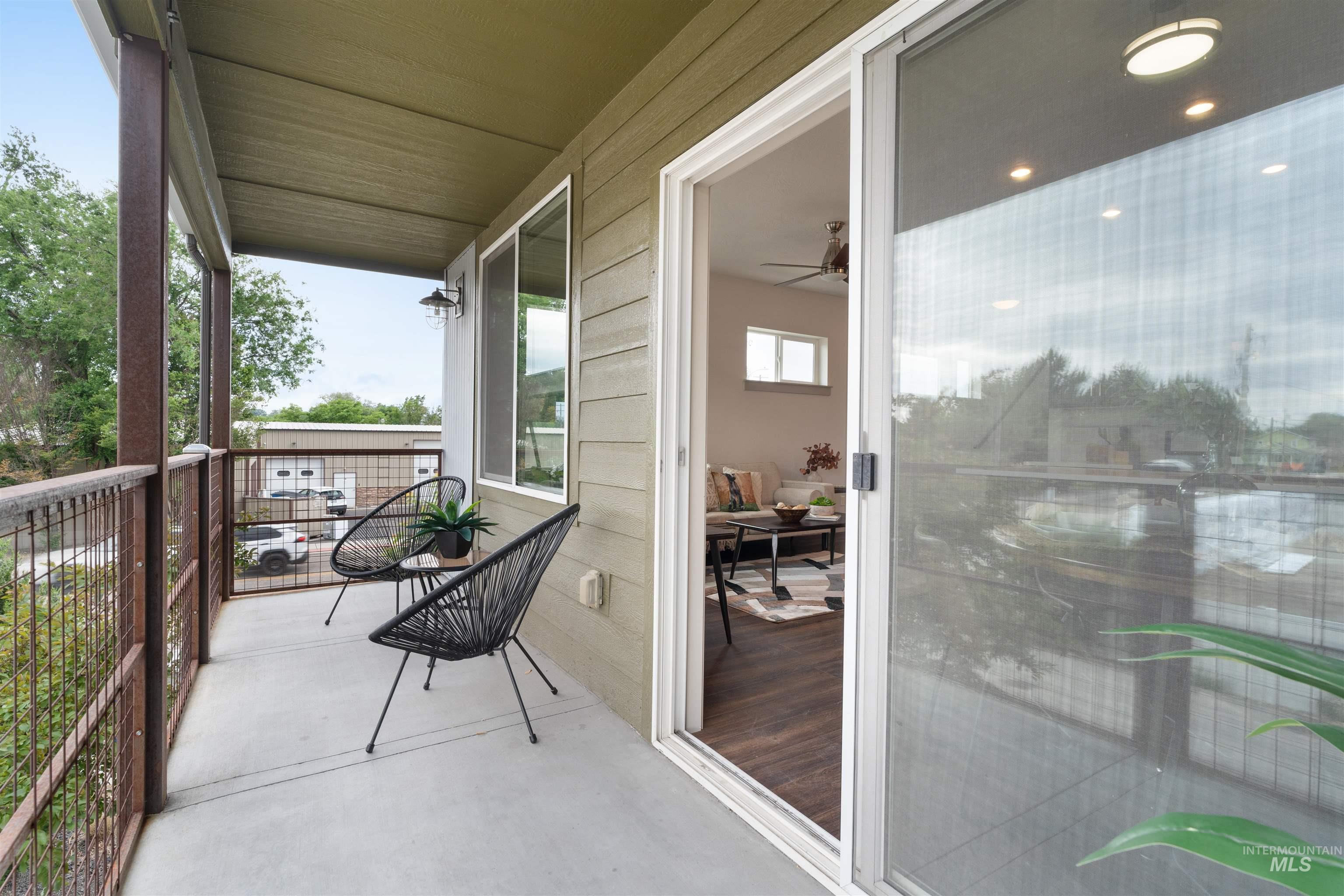 Covered balcony with concrete flooring, slatted siding, and metal railing