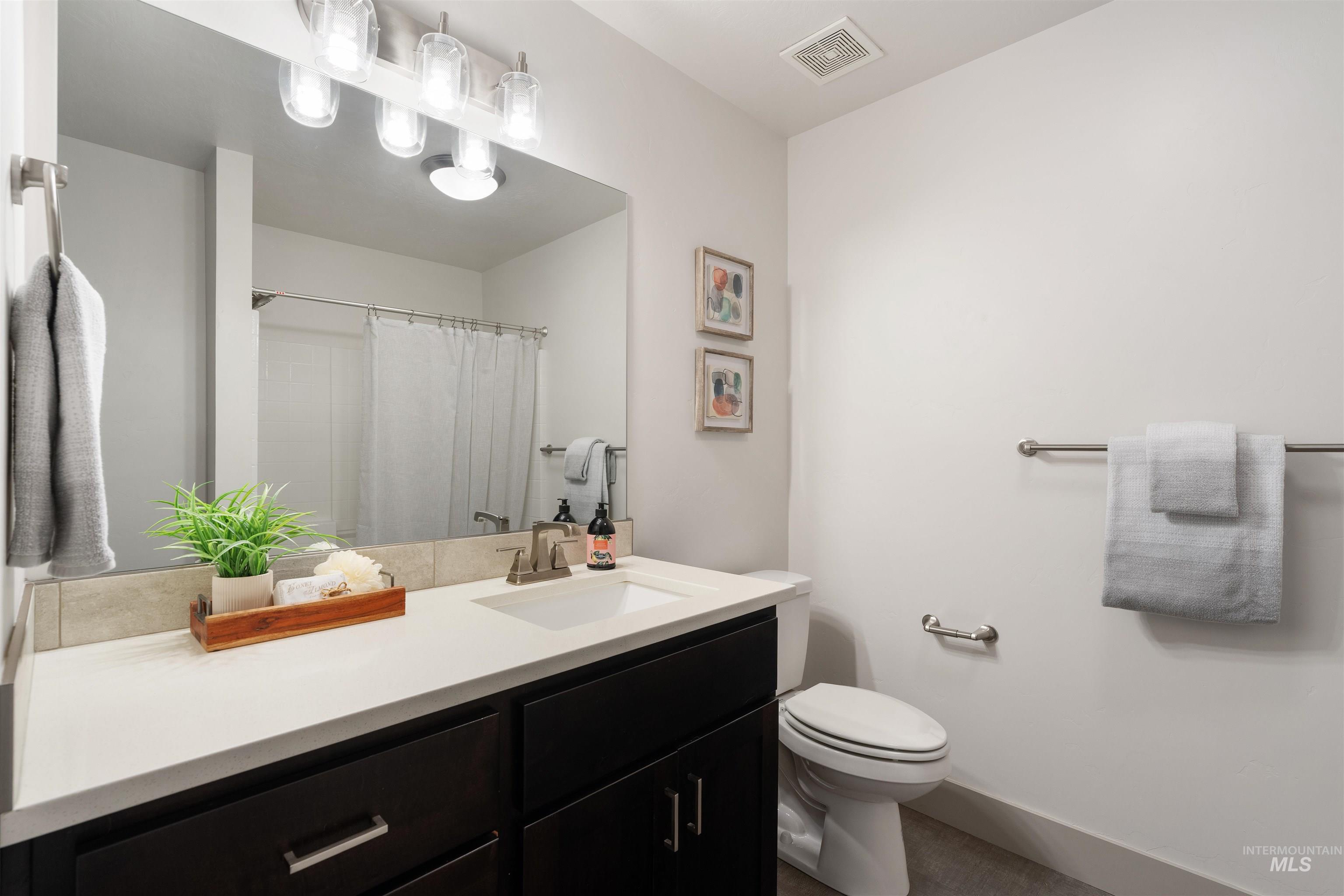 Bathroom featuring a vanity with dark wood-finish cabinetry, a white countertop, and an undermount sink