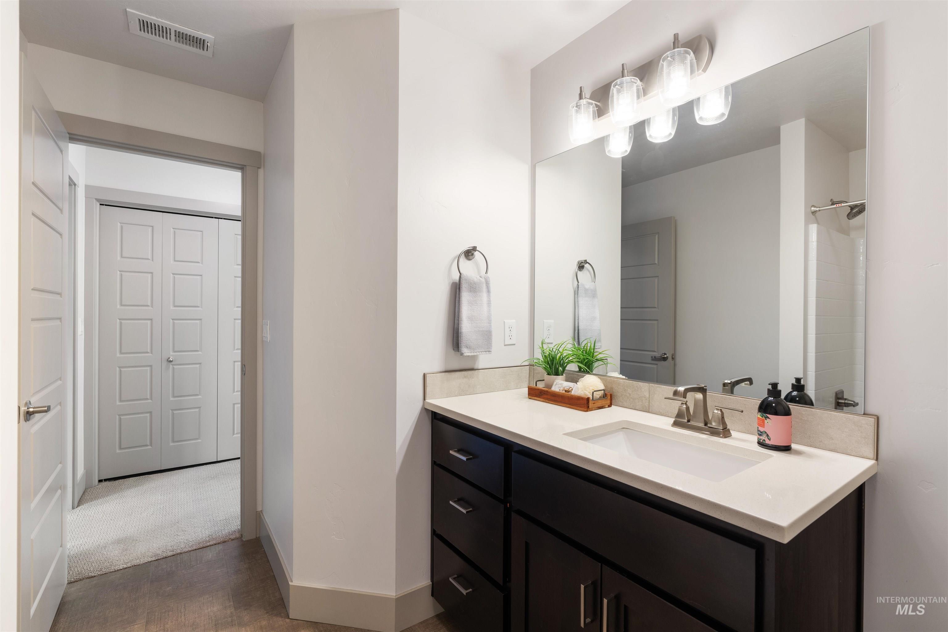 Bathroom vanity featuring a light-toned countertop, undermount sink, and brushed nickel faucet