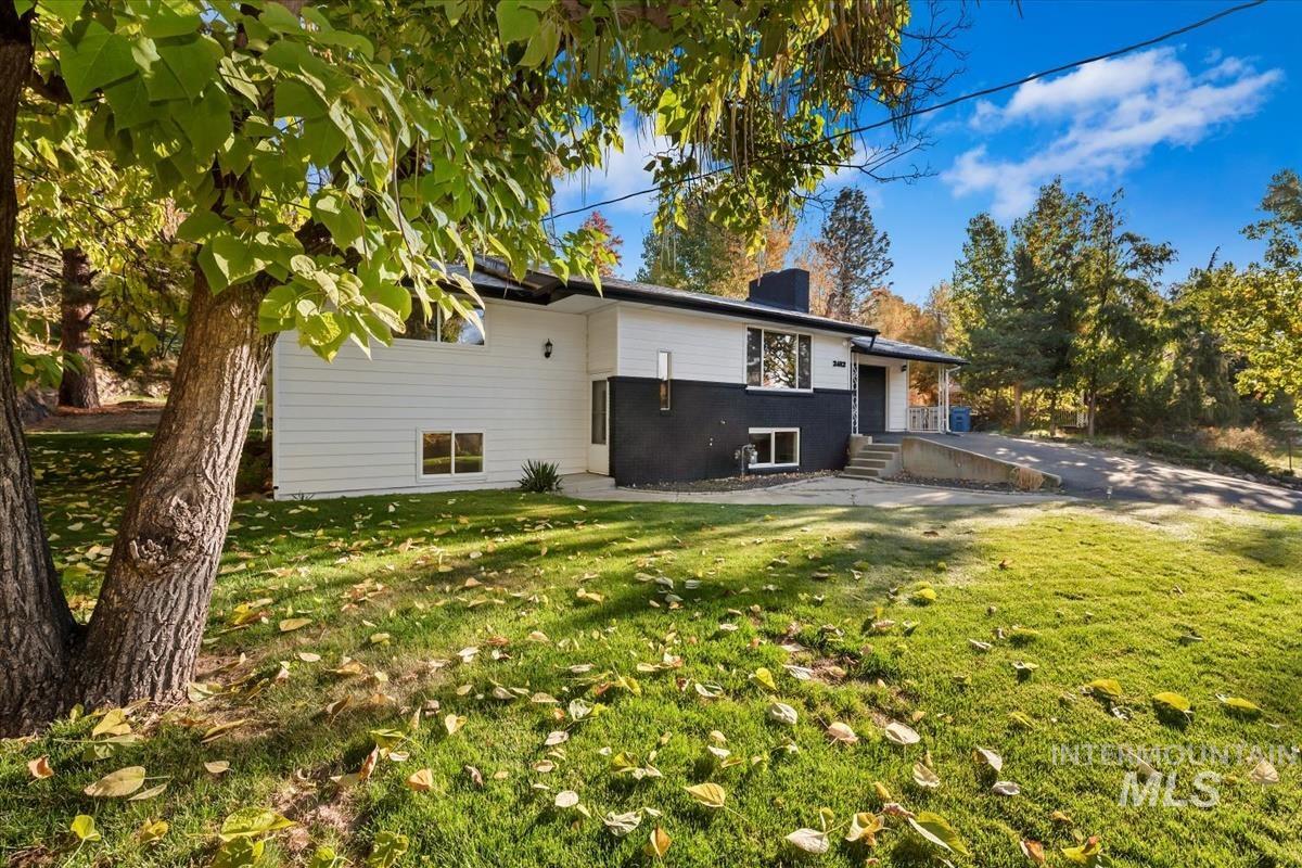 Back of house with a chimney, a lawn, and a patio