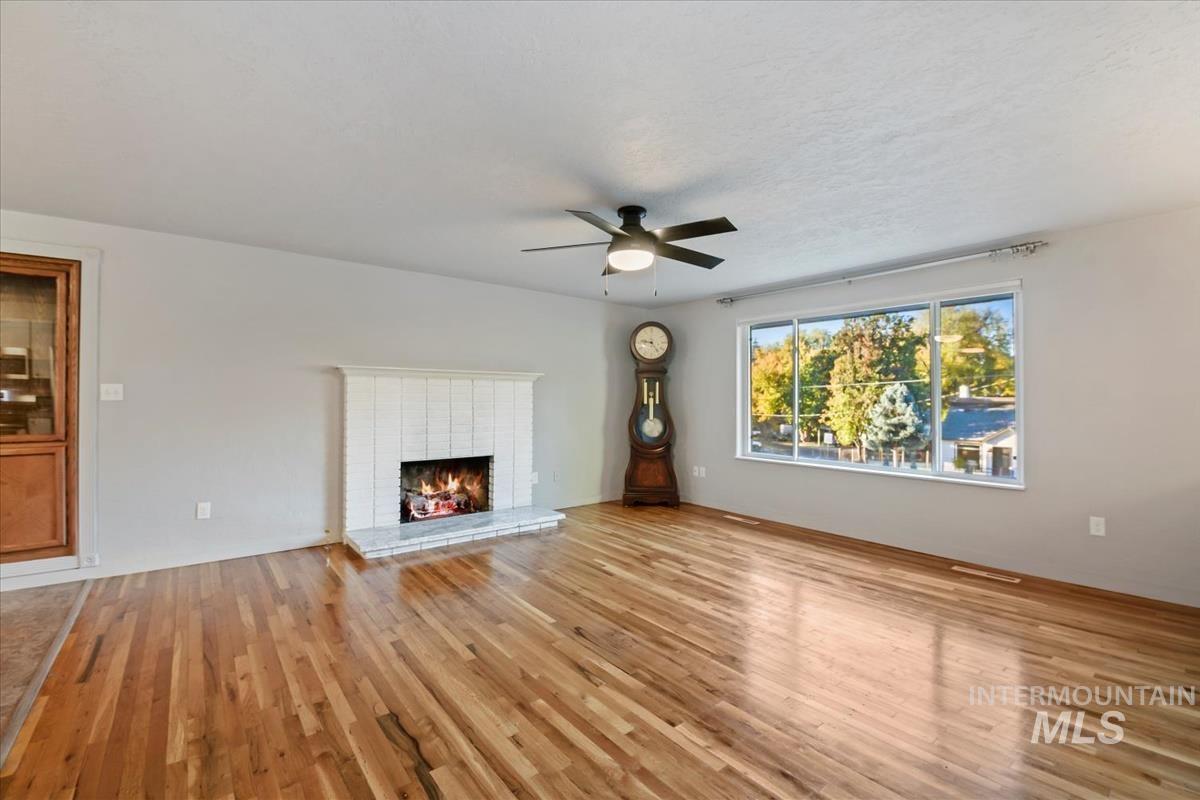 Unfurnished living room featuring a fireplace, light wood-style floors, and a ceiling fan