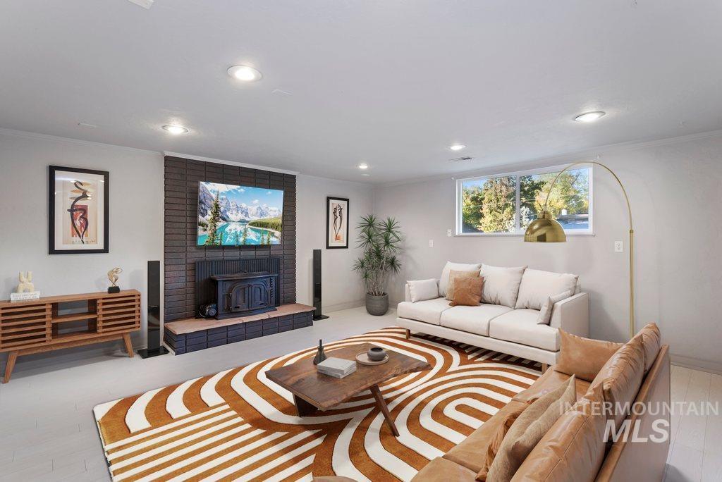 Living room with a wood stove, crown molding, recessed lighting, and wood finished floors