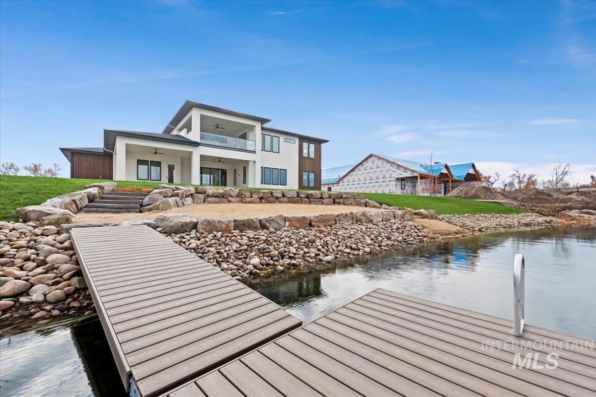 Dock area with a water view, a lawn, a balcony, and a patio