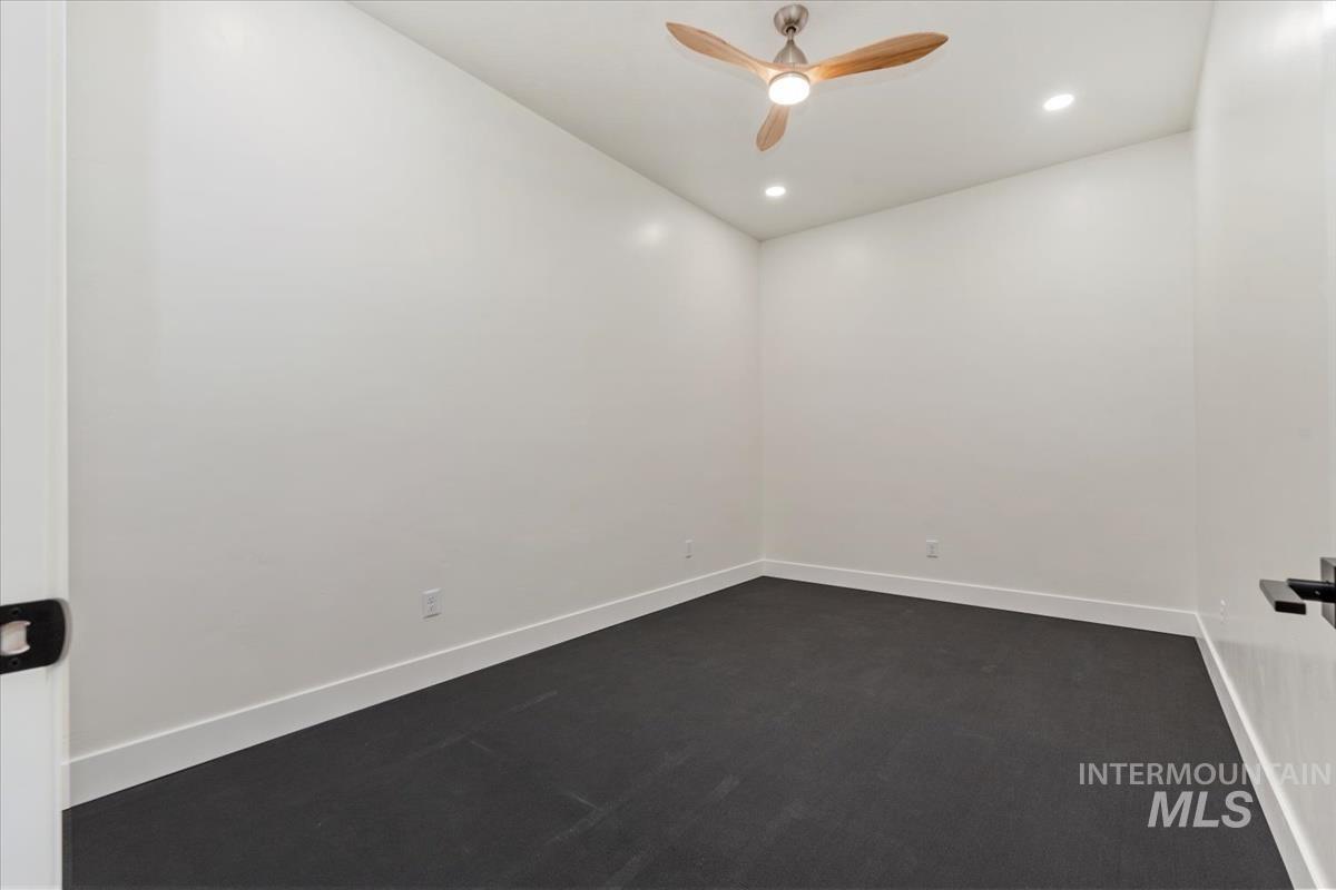 Unfurnished room with dark colored carpet, a ceiling fan, and recessed lighting