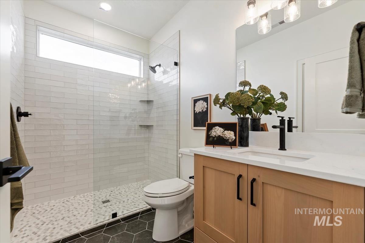 Full bathroom with vanity, walk in shower, and dark tile patterned flooring