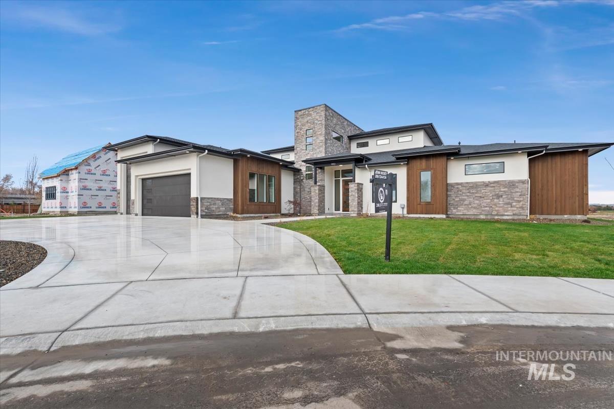View of front of property featuring stone siding, a front yard, driveway, an attached garage, and stucco siding