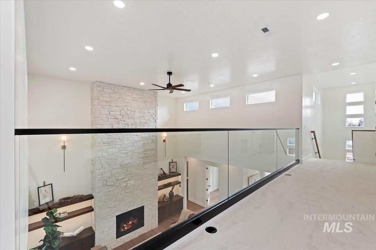 Staircase featuring a ceiling fan, carpet floors, and a stone fireplace