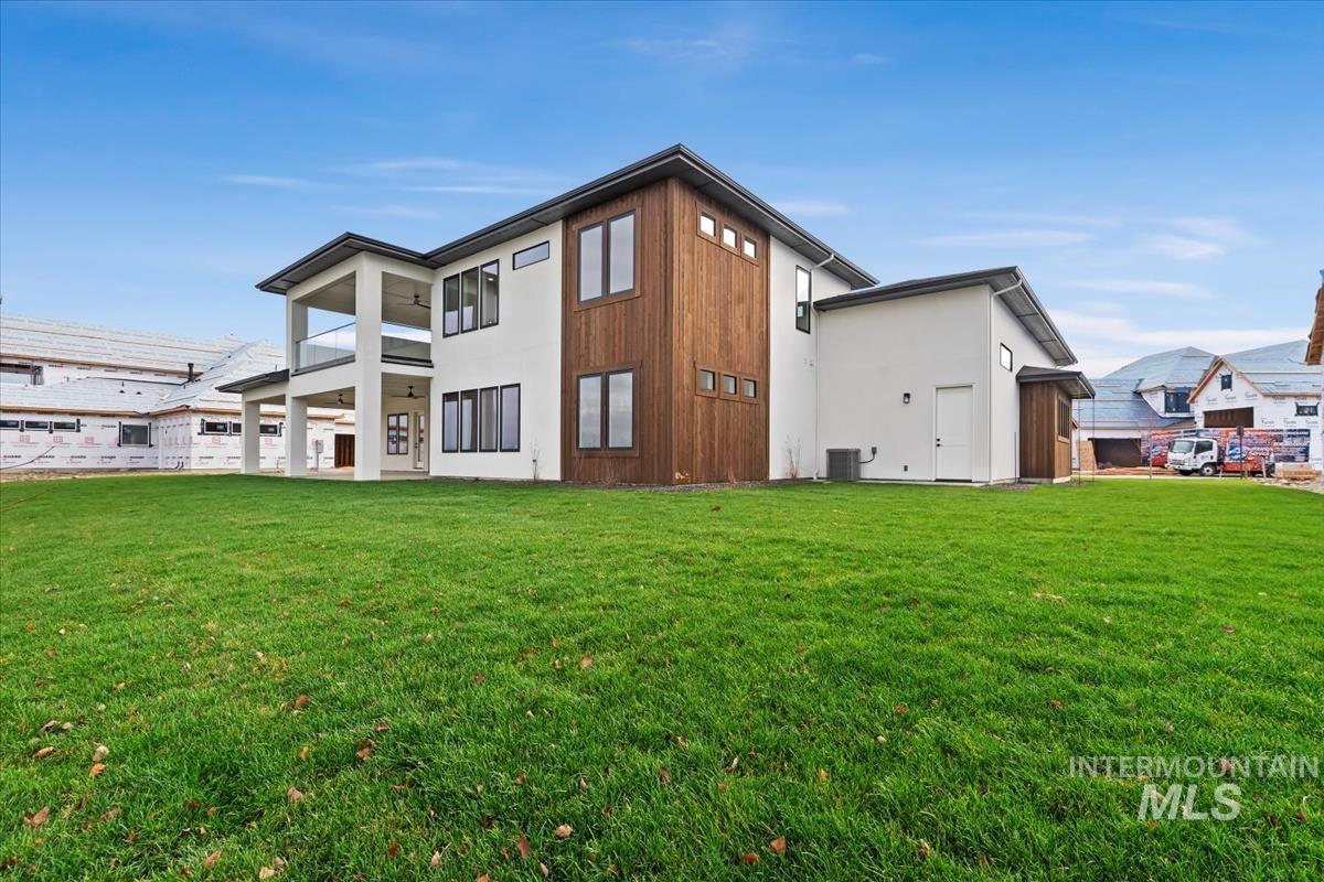 Rear view of house with a lawn, a balcony, and a patio