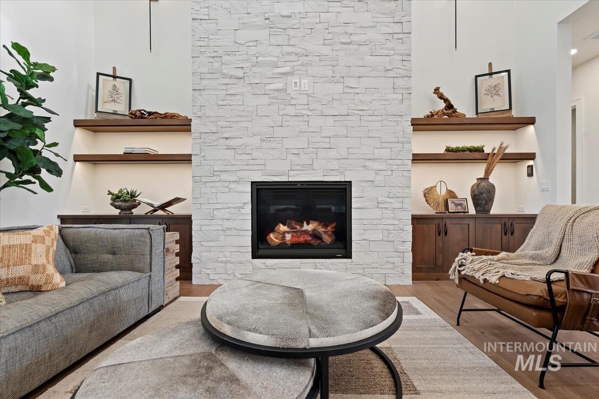 Sitting room featuring wood finished floors and a stone fireplace