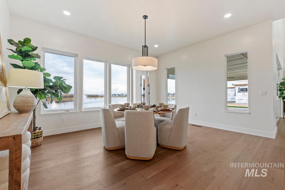 Dining space with light wood finished floors, a water view, and recessed lighting
