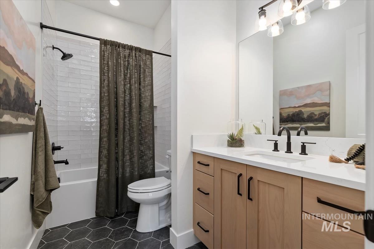 Full bathroom with shower / tub combo with curtain, vanity, and dark tile patterned flooring